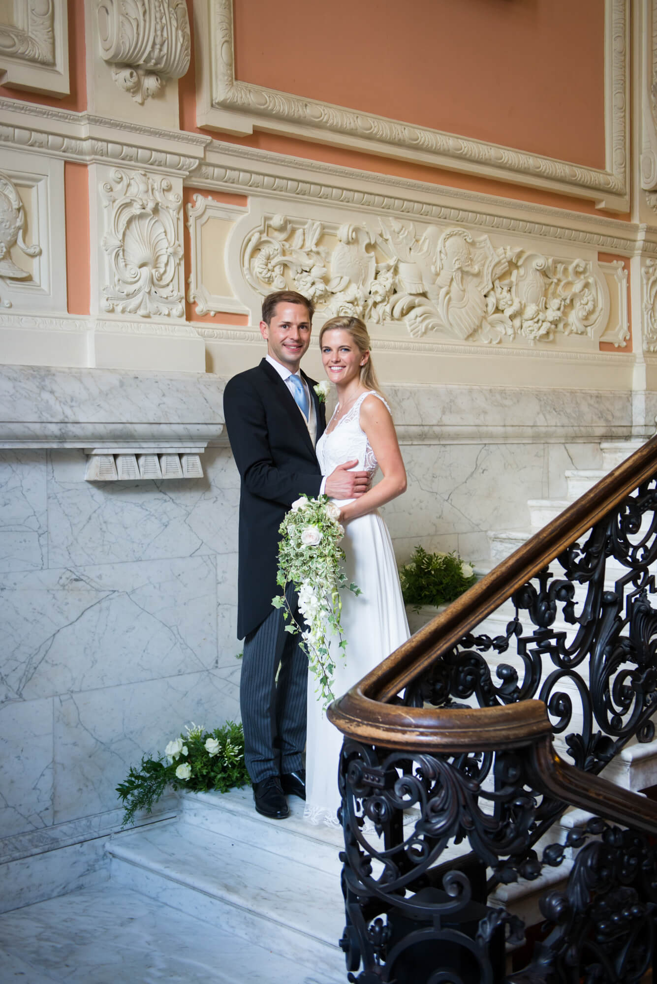 A bride and groom on the stairway in Dartmouth house having their wedding photography taken